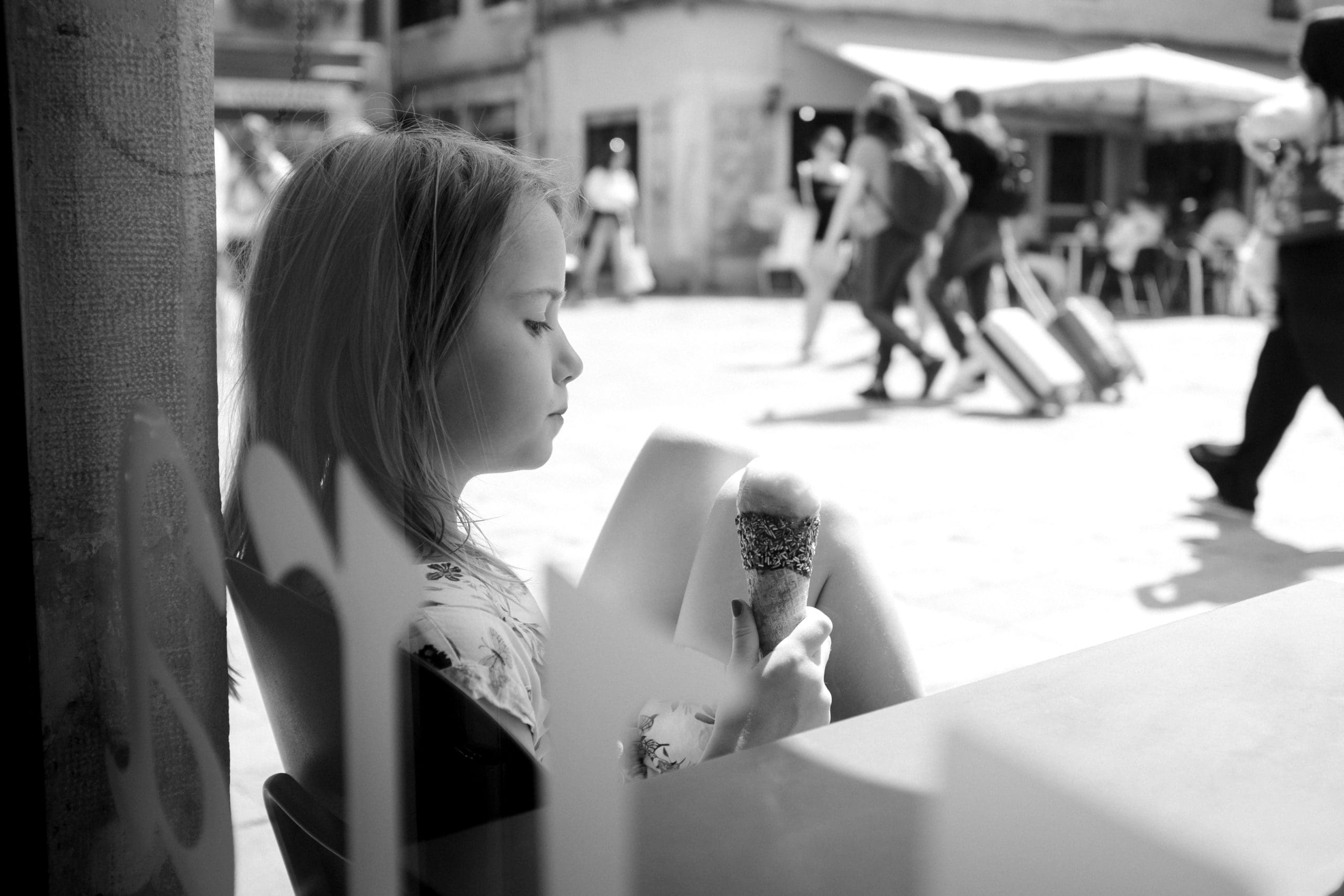 Mädchen betrachtet Eis in belebter Straße.