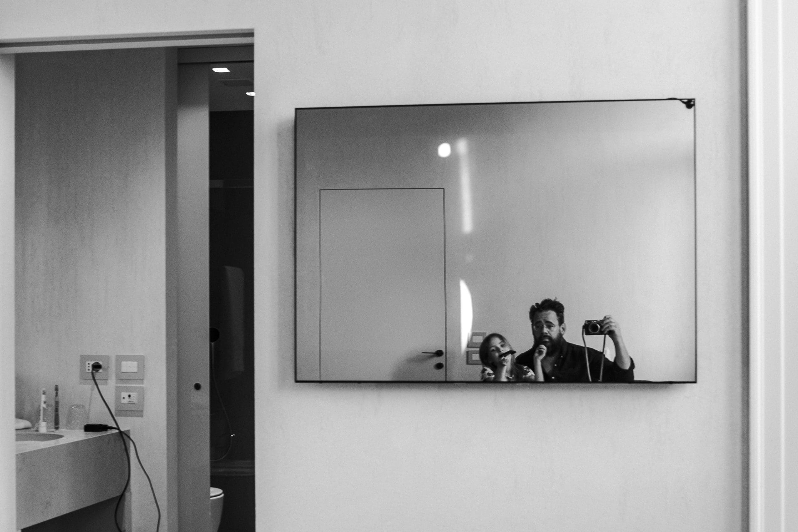 Personen spiegeln sich im Badezimmerspiegel.