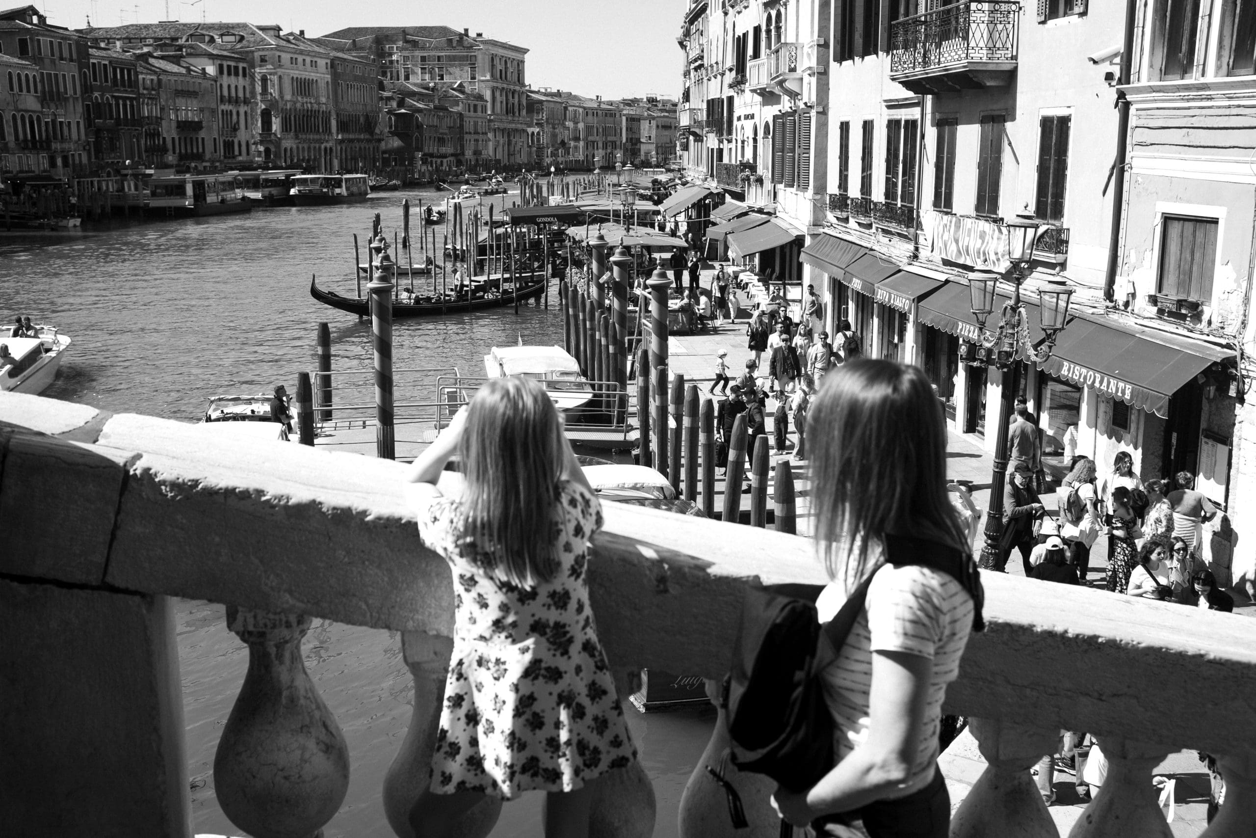 Zwei Personen blicken auf Venedigs belebten Kanal.